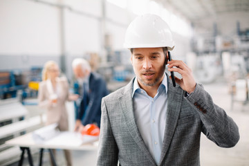 Portrait of handsome businessman talking to the phone. Man working in factory.	