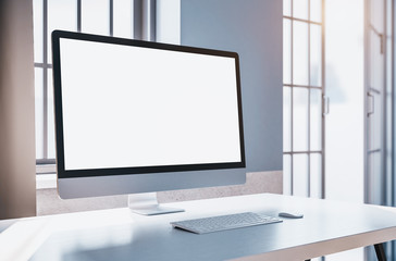 Office and computer with blank screen on table.