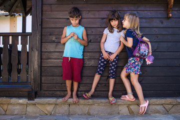 Kids gossiping. Girl whispering something to other girl, boy eavesdropping.