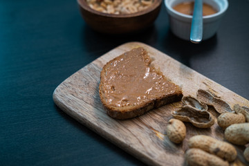 Peanuts and toast with peanut butter on a wooden table. Healthy snack. Close up view.