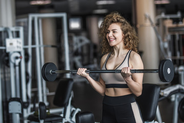 Fototapeta na wymiar Slim woman, blonde girl in sportwear with dumbbells in a gym, exercising with a barbell