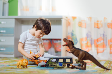 Adorable toddler playing with dinosaurs around lots of toys at kindergarten