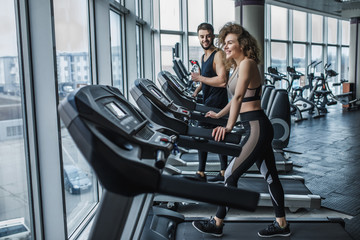Portrait of young sports couple making cardio workout in modern gym