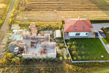 Top down aerial view of two private houses, one under construction with concrete foundament and...