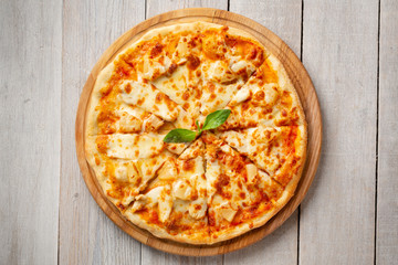 Tasty hawaiian pizza with chicken and pineapple on wooden cutting board. Top view