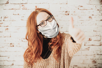 Young, attractive, red-haired woman with curly hair wearing a breathing mask in the pandemic