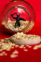 oatmeal in a bank and a black toy figurine of a warrior with a sword and shield red background photo