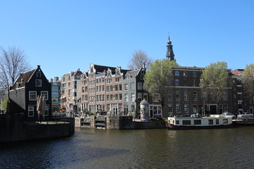Naklejka premium sunny view of buildings over water canal in Amsterdam