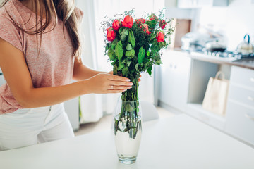Woman takes dead dry bouquet of roses flowers out of vase. Housewife taking care of coziness on kitchen.