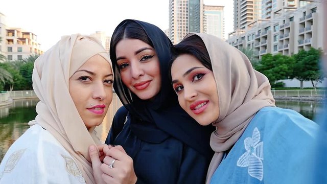 Three friends making shopping and spending time together in Dubai. Group of women wearing traditional uae abaya clothes outdoor