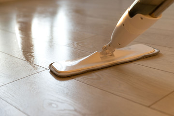 Person using spray mop pad and refillable bottle with cleaning solution, mopping the floor in apartment, doing homework cleaning routine. Close up. Housekeeping job © DimaBerlin