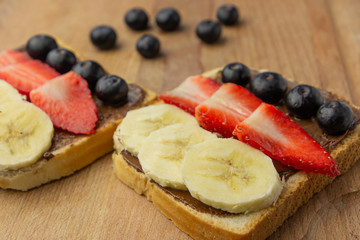 Breakfast with fruit sandwich with strawberry, banana, blueberry on a wooden board. Concept of healthy meal.
