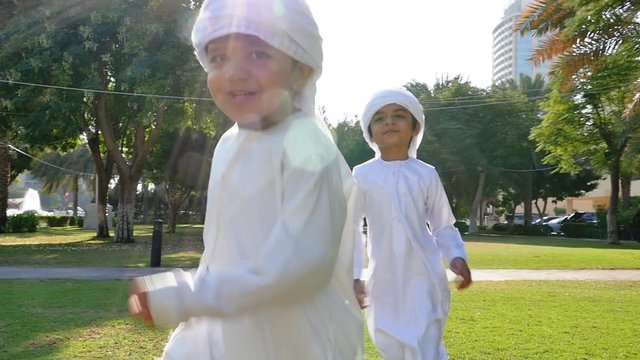 Kids playing outdoor on the meadow. Children wearing traditional united arab emirates kandura having fun