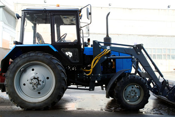 blue tractor with large wheels and front bucket