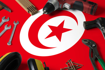Tunisia flag on repair tool concept wooden table background. Mechanical service theme with national objects.