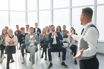 smiling speaker standing in front of an applauding audience