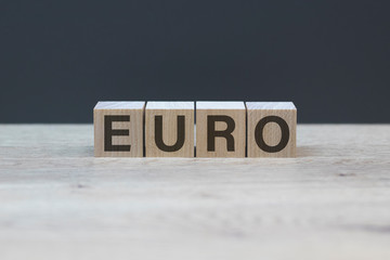 EURO word concept written on wooden cubes blocks lying on a light table and gray background