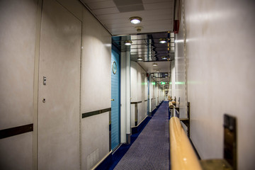 A long corridor in blue style with cabin doors on the deck of a modern passenger ferry