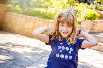 Cute, blond girl in blue t-shirt smiling shyly. Kids and parenthood concept