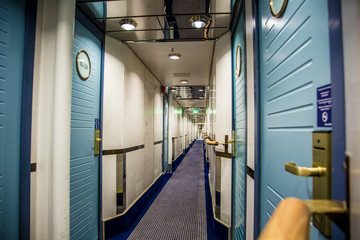 A long corridor in blue style with cabin doors on the deck of a modern passenger ferry