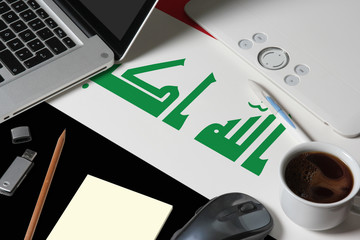 Iraq national flag on top view work space of creative designer with laptop, computer keyboard, usb drive, graphic tablet, coffee cup, mouse on wooden table.