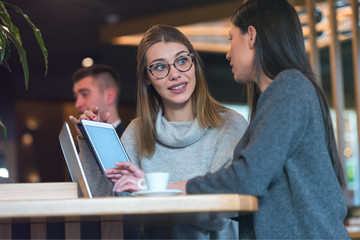 Two Young business women talking with each other about new projects at a coffee bar at caffe brake.
