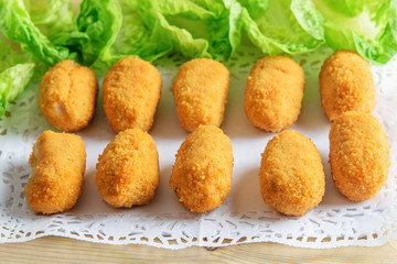 Croquettes and green lettuce on the white dish closeup. Light fast food concept.