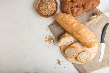Sliced bread with different kinds of fresh baked bread on a white wooden background. top view, copy space.
