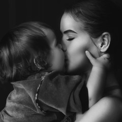 Black and white photo. Little girl kisses her mom.