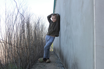 A little boy stands near the wall as a model.