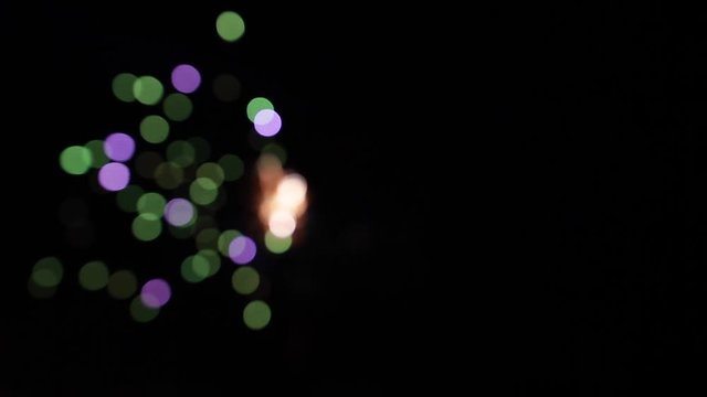 Bright colorful fireworks turn to multicolor bokeh lights at holiday dark summer night.