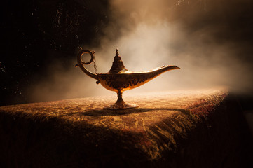 Lamp of wishes concept. Antique Aladdin arabian nights genie style oil lamp with soft light white...