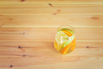 Glass of white wine sangria with orange, lemon and green apple on wooden table. Selective focus.