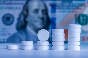 pills stacked against money background, toned in blue