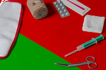 Belarus flag with first aid medical kit on wooden table background. National healthcare system concept, medical theme.