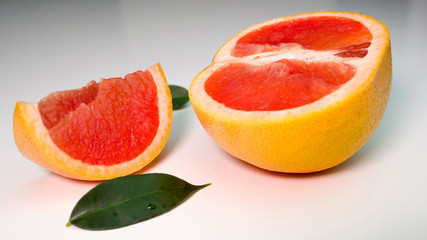 Fototapeta na wymiar ripe grapefruit on a white table with a leaf of green