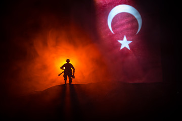 Silhouette of soldier with rifle against a turkish flag. Selective focus