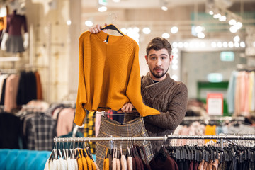 A young man helping his girlfriend to find the right outfit in a clothing store