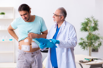 Injured young man visiting experienced male doctor