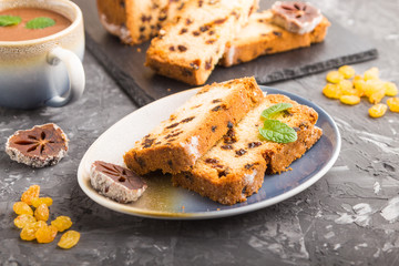 Homemade cake with raisins, dried persimmon and a cup of hot chocolate on a black concrete background. Side view, copy space, selective focus.