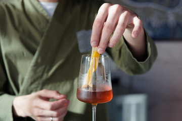 Male bartender is adding lemon zest to cocktail