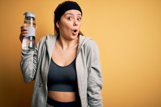 Young beautiful sportswoman doing sport wearing sportswear drinking bottle with water scared in shock with a surprise face, afraid and excited with fear expression