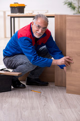 Old male carpenter working indoors
