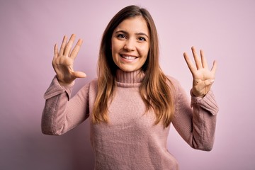 Beautiful young woman wearing turtleneck sweater over pink isolated background showing and pointing up with fingers number nine while smiling confident and happy.