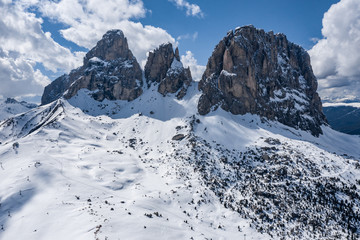 Fototapeta na wymiar Aerial view of twisting road in a mountains of Italy, Dolomites, is serpentine among the snow-covered hills, is famous place among skiers and fans to understand a known by sports cars, mountains peak