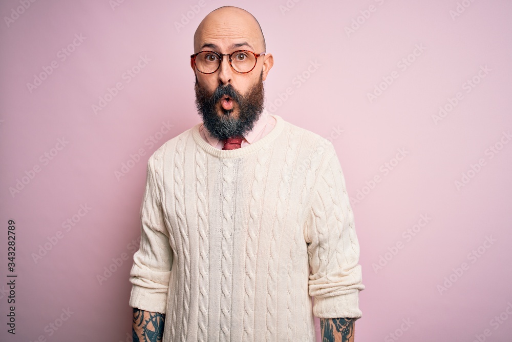 Sticker Handsome bald man with beard and tattoo wearing glasses and sweater over pink background afraid and shocked with surprise expression, fear and excited face.