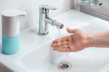 Hand washing with soapy water in the bathroom. A young guy washes his hands with soap. The fight against coronavirus.