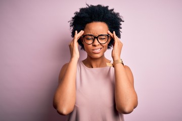 Young beautiful African American afro woman with curly hair wearing t-shirt and glasses suffering from headache desperate and stressed because pain and migraine. Hands on head.