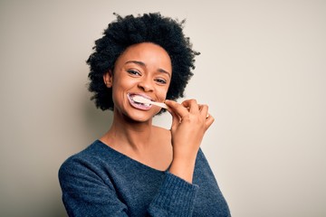 African american woman brushing her teeth using tooth brush and oral paste, cleaning teeth and...