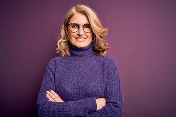 Middle age beautiful blonde woman wearing casual purple turtleneck sweater and glasses happy face...